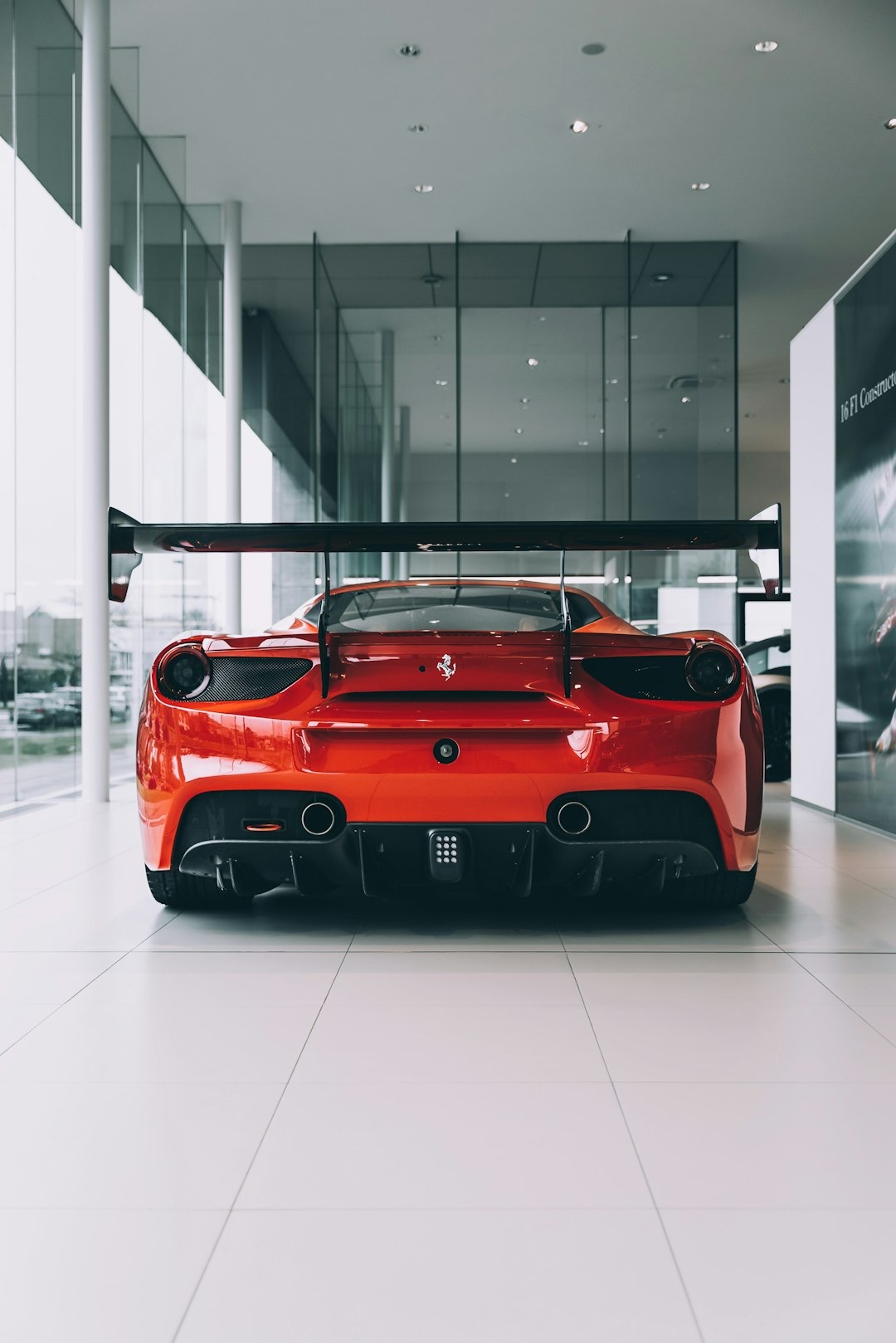 Red sports car with a spoiler parked in a showroom.